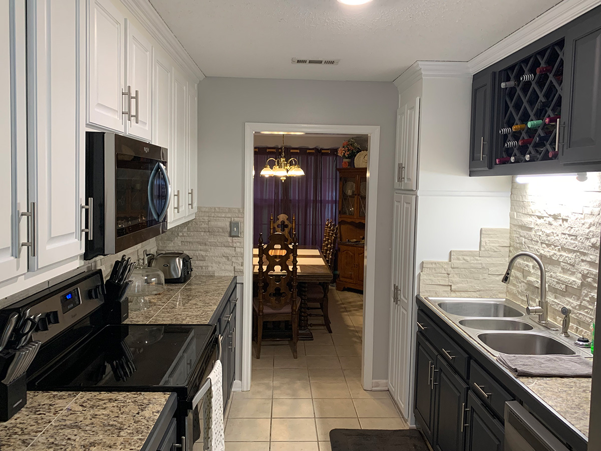 Kitchen remodel with black cabinets and a stone backsplash.
